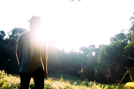 man standing on grass field with sun gazing