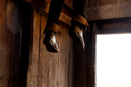 person feet with brown leather boots dangling by the entrance