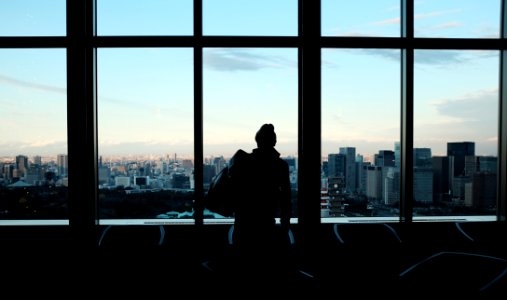 silhouette of person looking to glass window