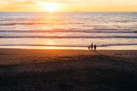 golden hour photography of three people on beach photo