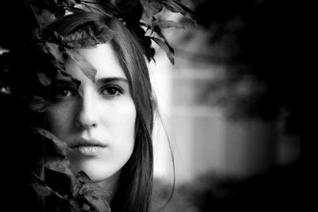 grayscale photo of woman beside leaves