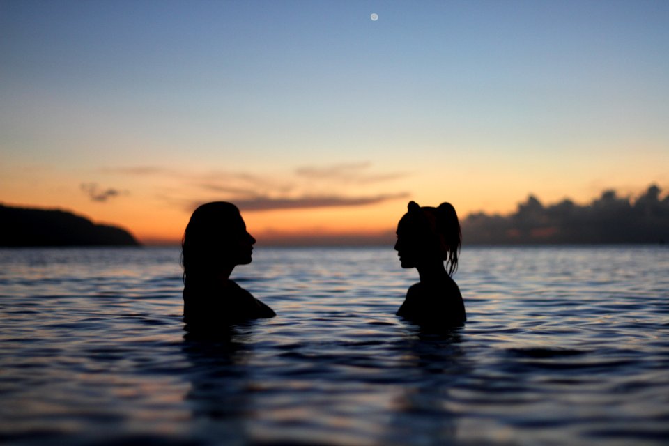 silhouette of two woman face to face in body water