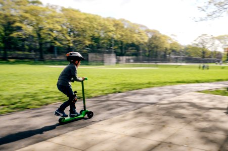 boy riding green kick scooter photo