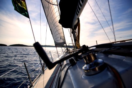 Reel on sailboat with sails sailing on water with horizon in the background photo