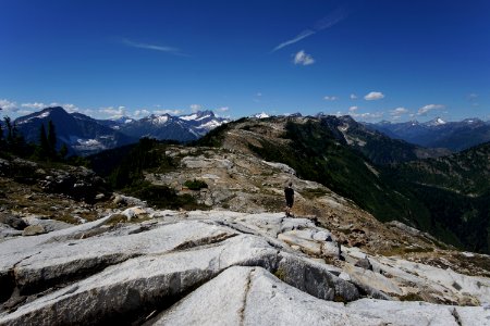 person standing on rock facing mountains during daytime photo