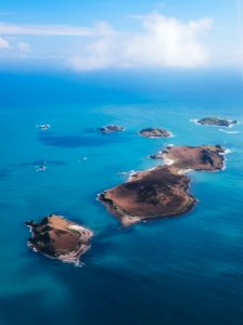 brown island on body of water under cloudy sky