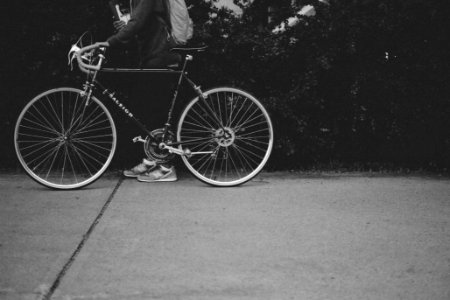 grayscale photo of person holding a bicycle photo