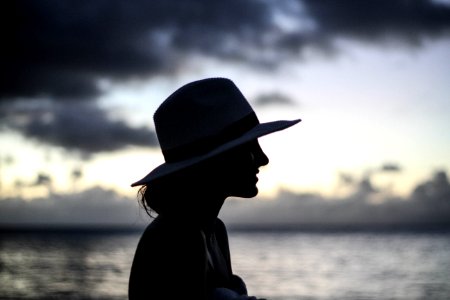 silhouette of woman standing beside body of water photo