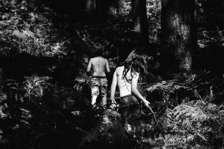 grayscale photography of two topless persons standing at the forest during day photo