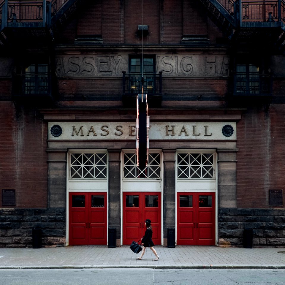 woman walking on street near red Masse Hall during daytime photo