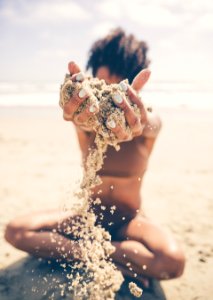 selective focus photo of woman sitting and raising sand during daytime photo