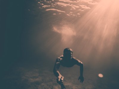man holding black monopod while under the sea photo