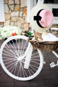 brown wicker basket with white, pink, and black sunhat besides white bike photo