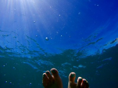 human feet on body of water during daytime