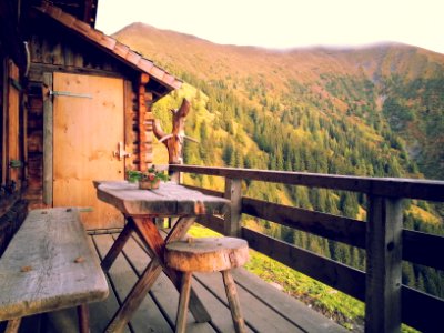 brown wooden table and bench near wooden balcony overlooking mountain at daytime photo