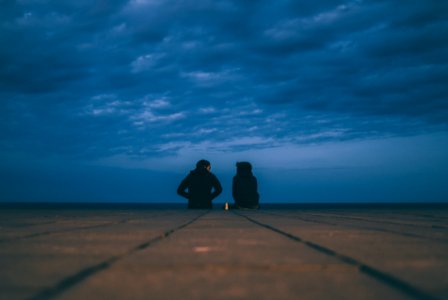 two people wearing black jackets sitting on floor photo