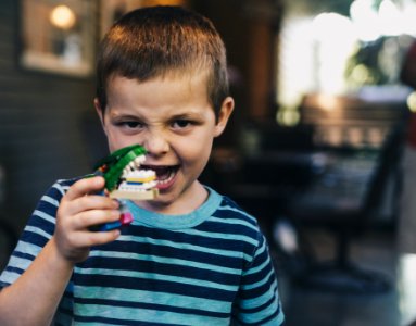 boy wearing teal and black striped t-shirt holding toy photo