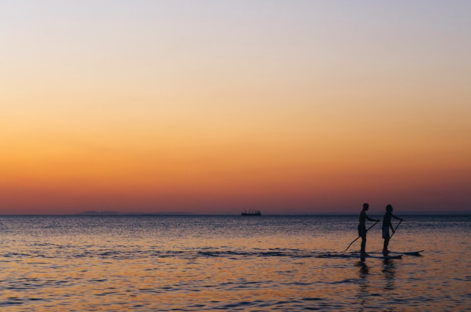 two person kayaked on ocean during golden hour
