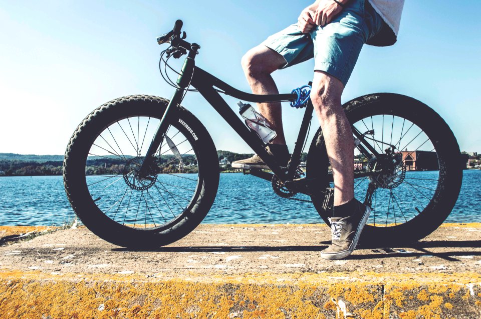 man on black fat bike on brown concrete platform overlooking body of water at daytime