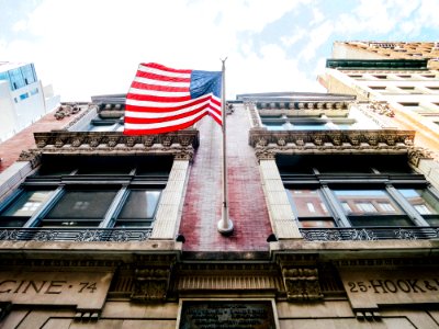 low angle photography of waving U.S.A. flag hang on bricks wall photo