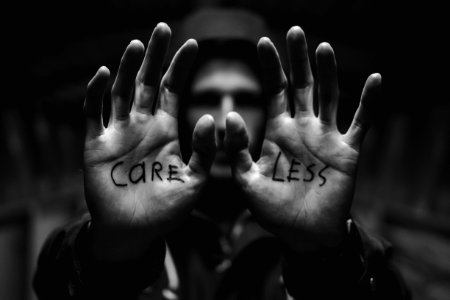 gray scale photography of man raising both hands with care less text on palm photo