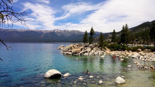calm body of water surrounded with rocks and trees under blue sky photo