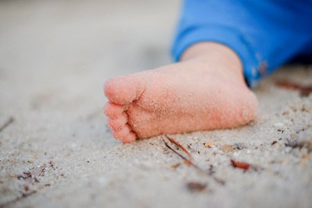 shallow focus photography of toddler's foot with sand