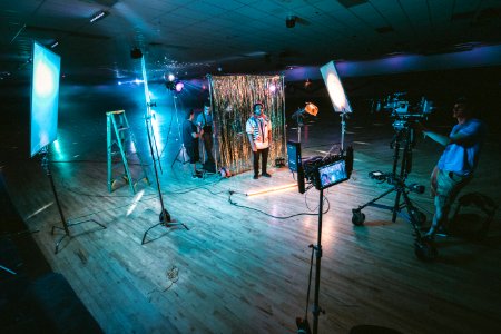 man standing in front of cameras with string lights background photo