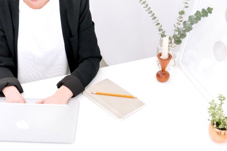 A person in business attire typing on a Macbook.