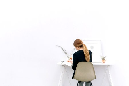 A long-haired woman sitting at a computer desk.