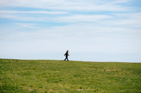 child walking on green grass field photo