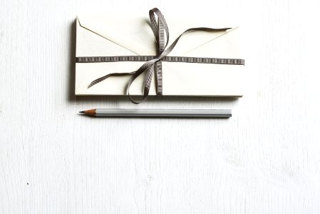 white envelop and gray pencil on white panel