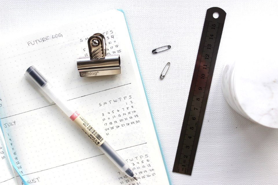 An agenda with a pen, clip, ruler and other items.