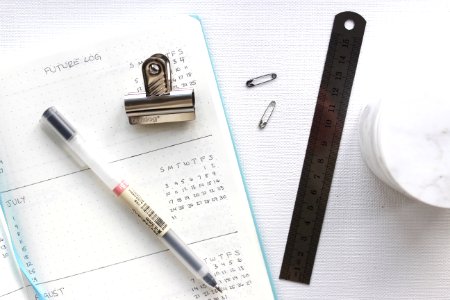 An agenda with a pen, clip, ruler and other items.
