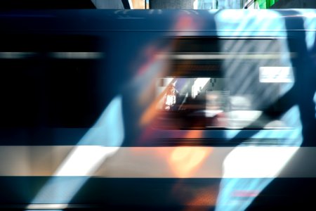 A blue train car blurring past briefly framing a person waiting photo