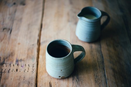 white ceramic mug with brown and white liquid inside on brown wooden surface photo