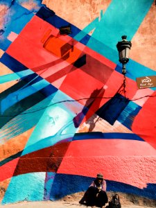 man sitting on wall with artwork and lamp