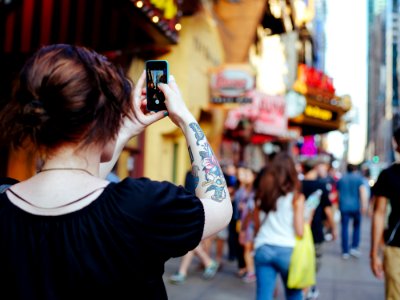 focus photo of woman in black cap-sleeved shirt holding smartphone while taking photo photo