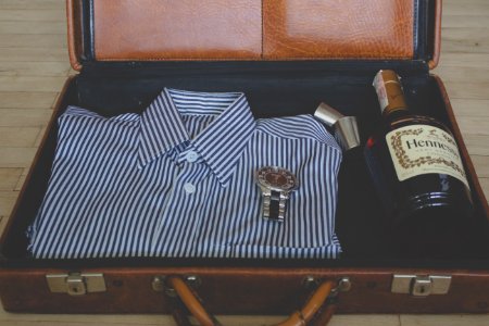 watch, whisky bottle and sport shit in suitcase photo