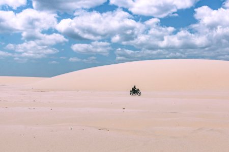 person rides on motorcycle under white sky
