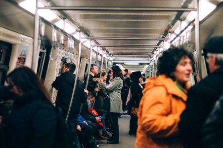 woman standing inside train surrounded by people photo