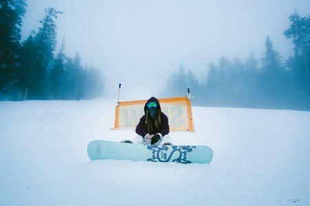 person with snowboard sitting on snowfield at daytime photo