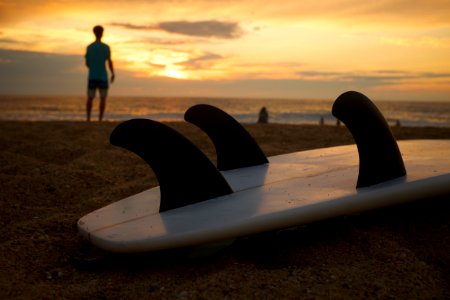 white and black surfboard on white sand during sunsetr photo