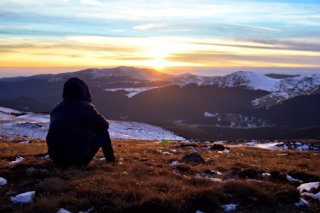 person standing on grass facing on mountain