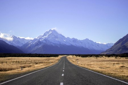 landscape photography of empty dessert road under blue calm sky with mountain view photo