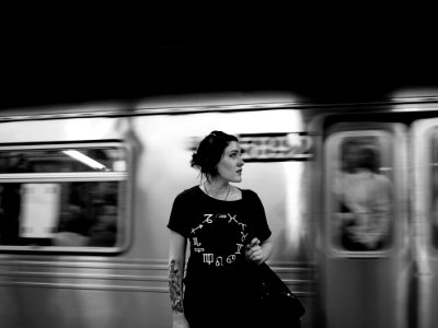 grayscale photography of woman standing near train