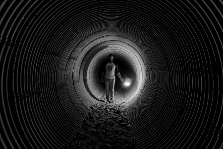 grayscale photography of person walking on tunnel photo