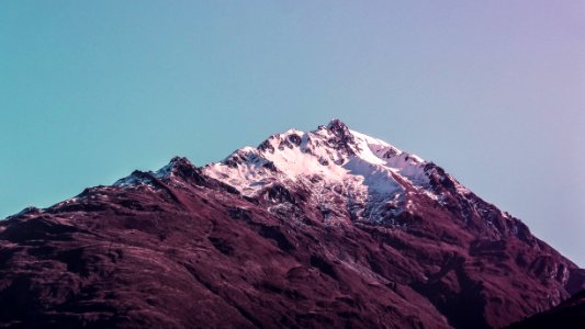 mountain with snow cap under gray clouds at daytime