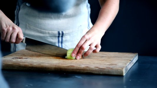 person slicing green vegetable on chopping board photo