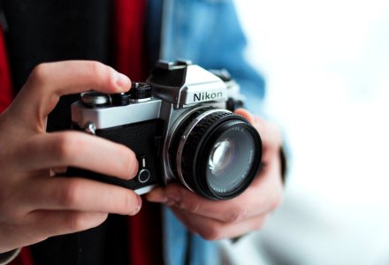person holding black and gray Nikon DSLR camera photo